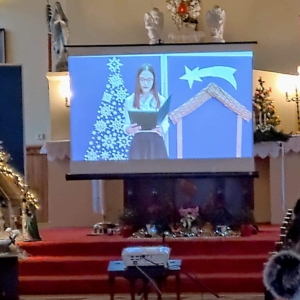 Uczennica czyta informacje o tradycji Świąt Bożego Narodzenia na tle dekoracji światecznej