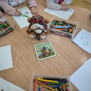 Dzieci rysują ilustracje do wysłuchanej książki  "Krecik i sikoreczka". Na zdjęciu widoczna maskotka projektu
