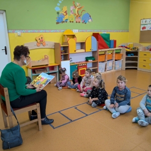 Zdjęcie przedstawia nauczyciela-bibliotekarza czytającego bajki dzieciom z przedszkola w ramach obchodów Miesiąca Bibliotek Szkolnych